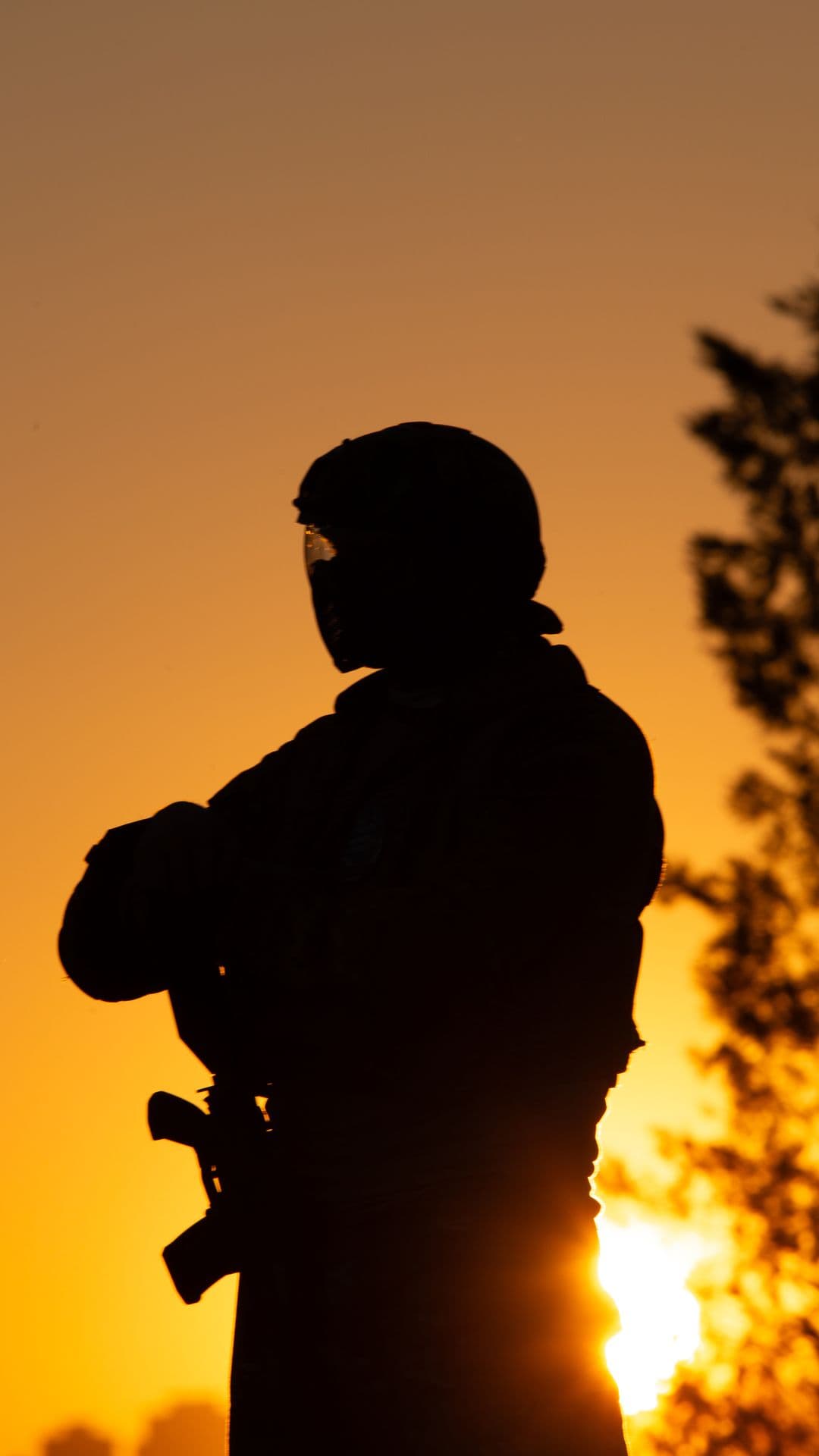 Paintball player silhouetted against the sunrise